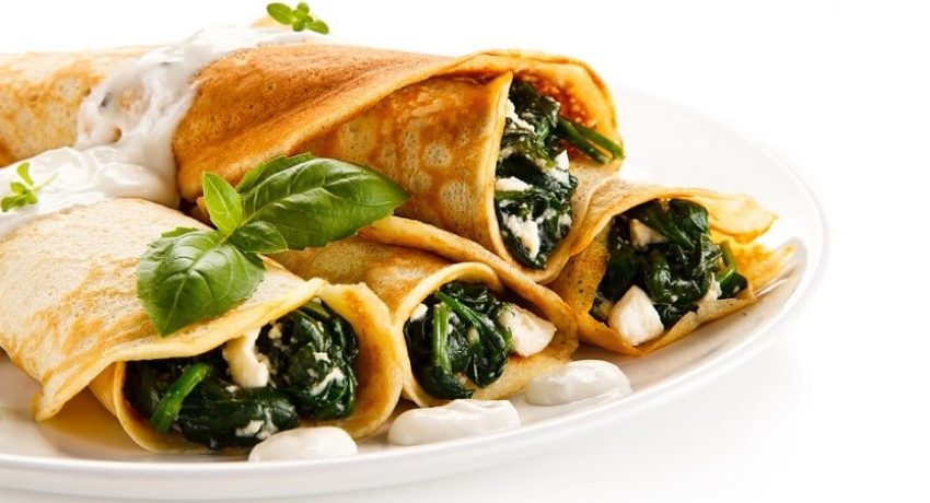 Crepes with spinach and feta cheese on white background